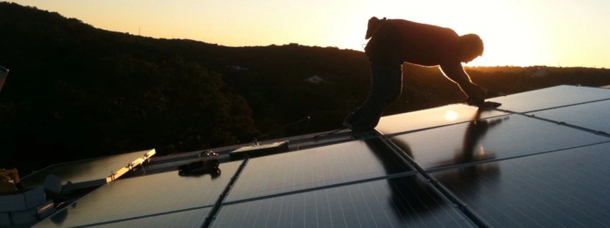 An Advanced Solar installer working on a rooftop array at sunset